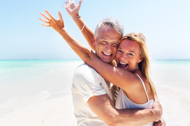 Portrait of excited mature woman in her husbands arms at the beach